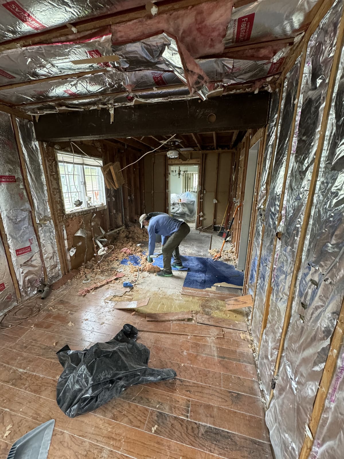 Worker pulling flooring in a room stripped to the studs