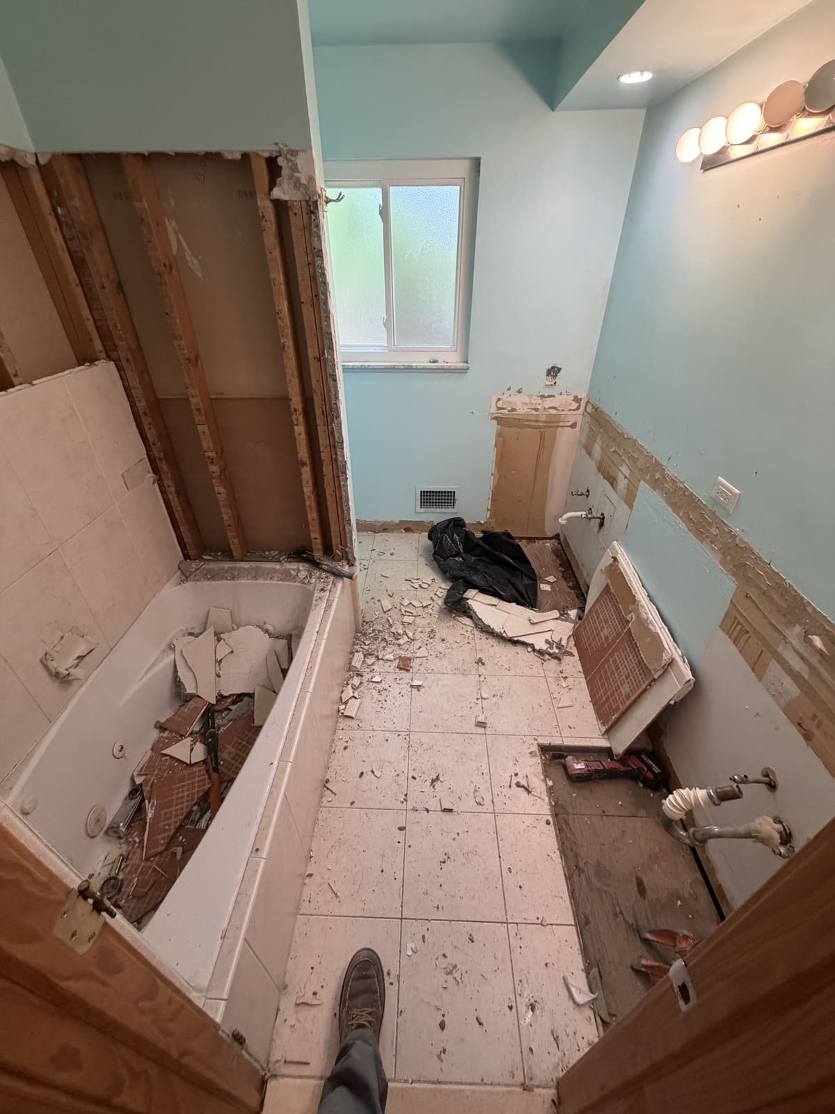 Bathroom demolition with the tub still set and tile and drywall coming out