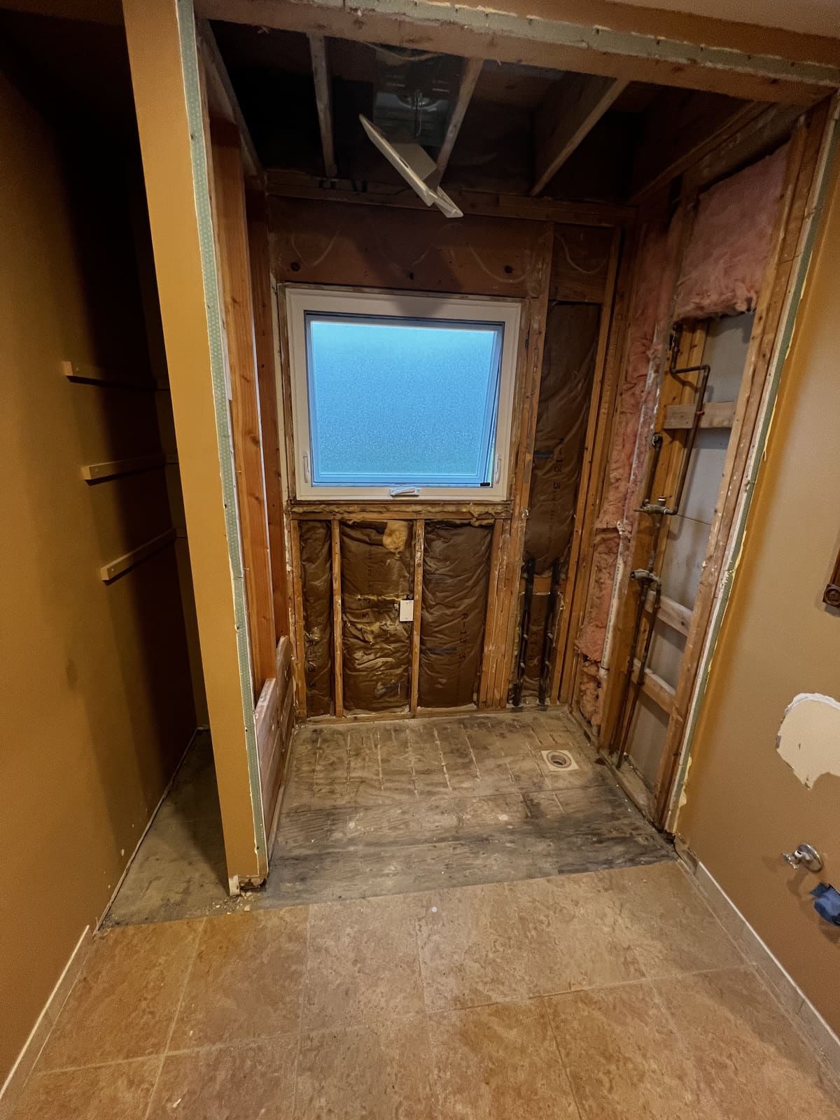 Small room stripped to the studs with the window left in place