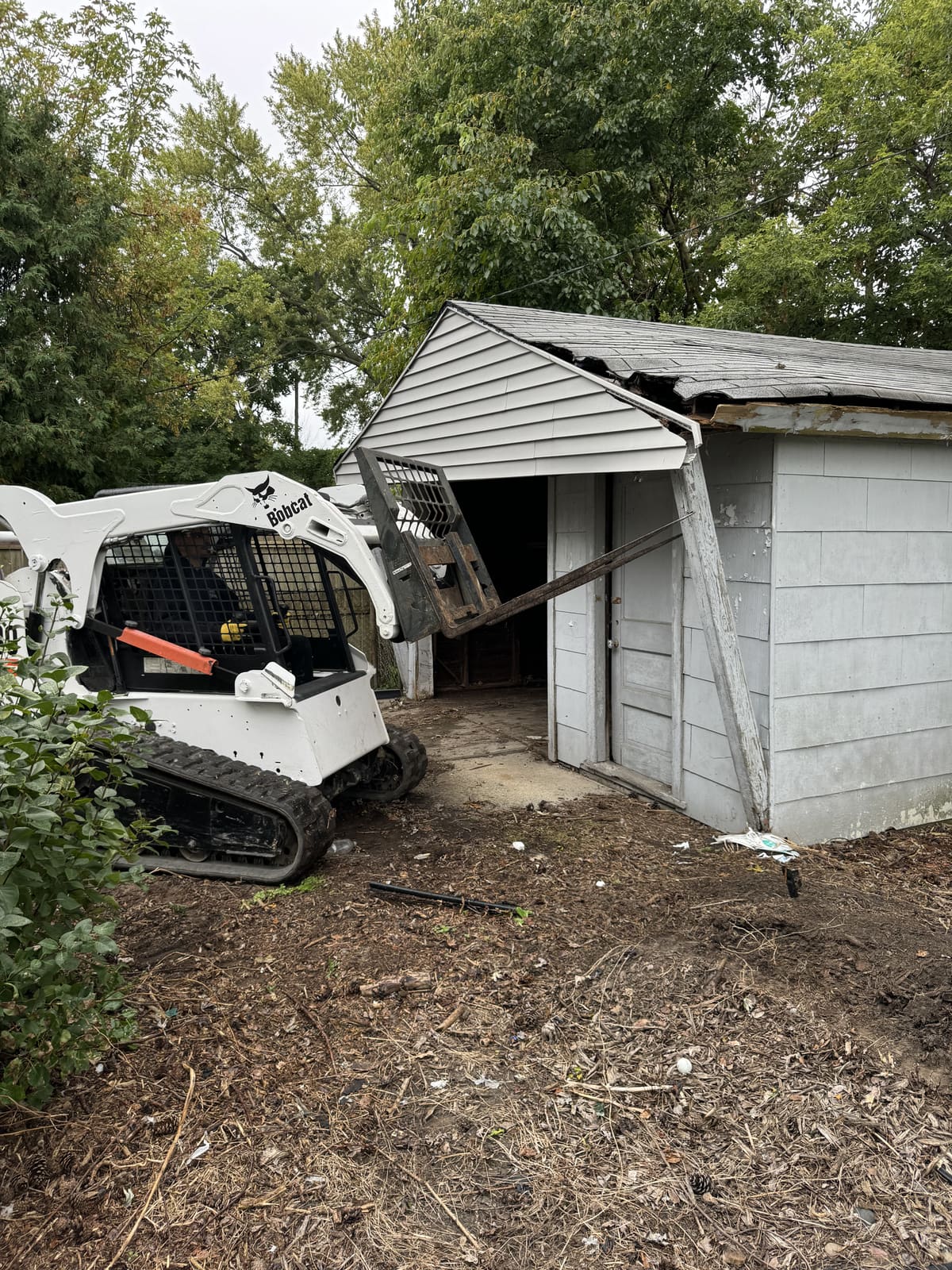 Skid steer tearing into the front of a detached garage
