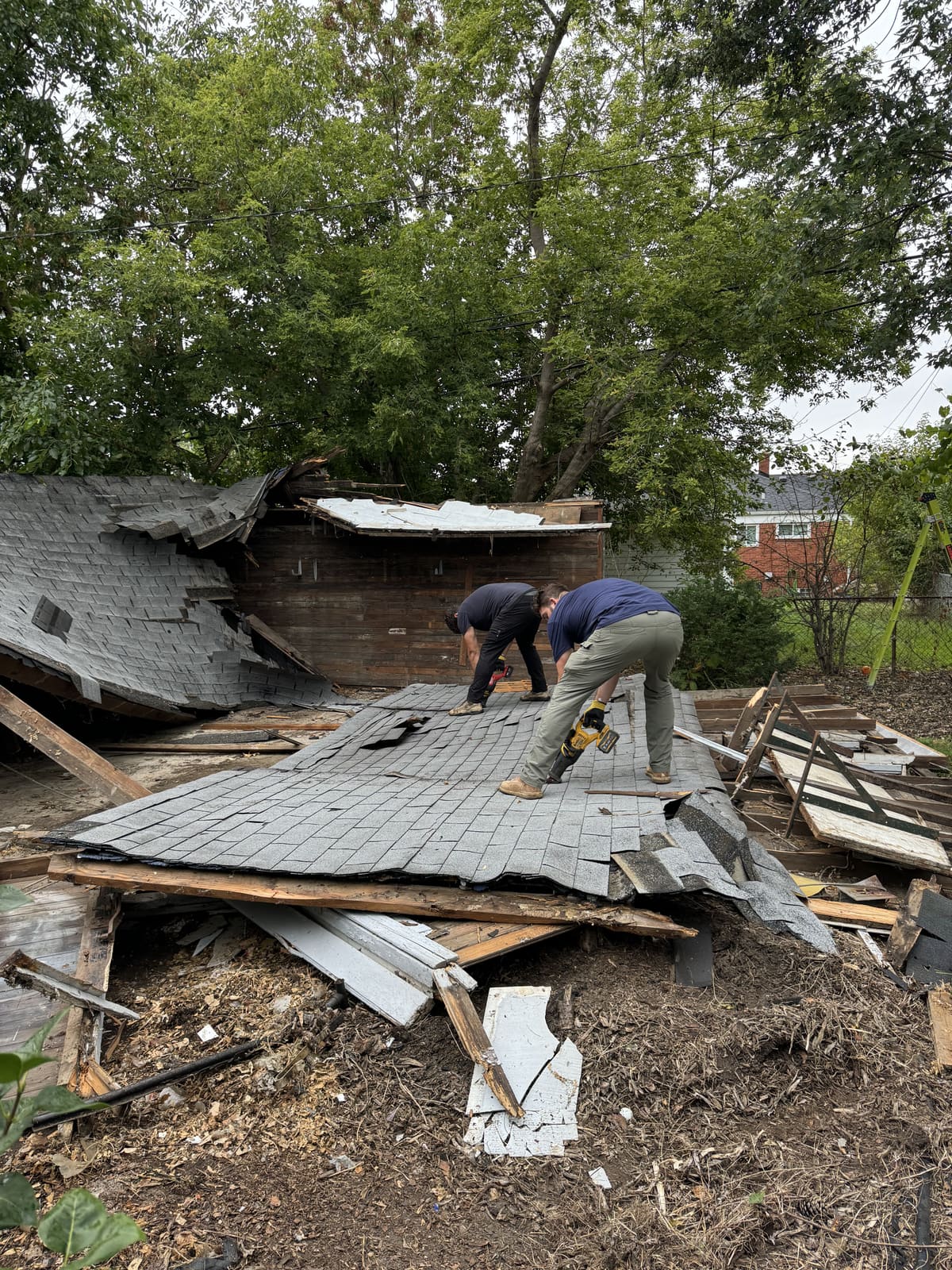 Two workers taking apart a collapsed roof on a residential demolition