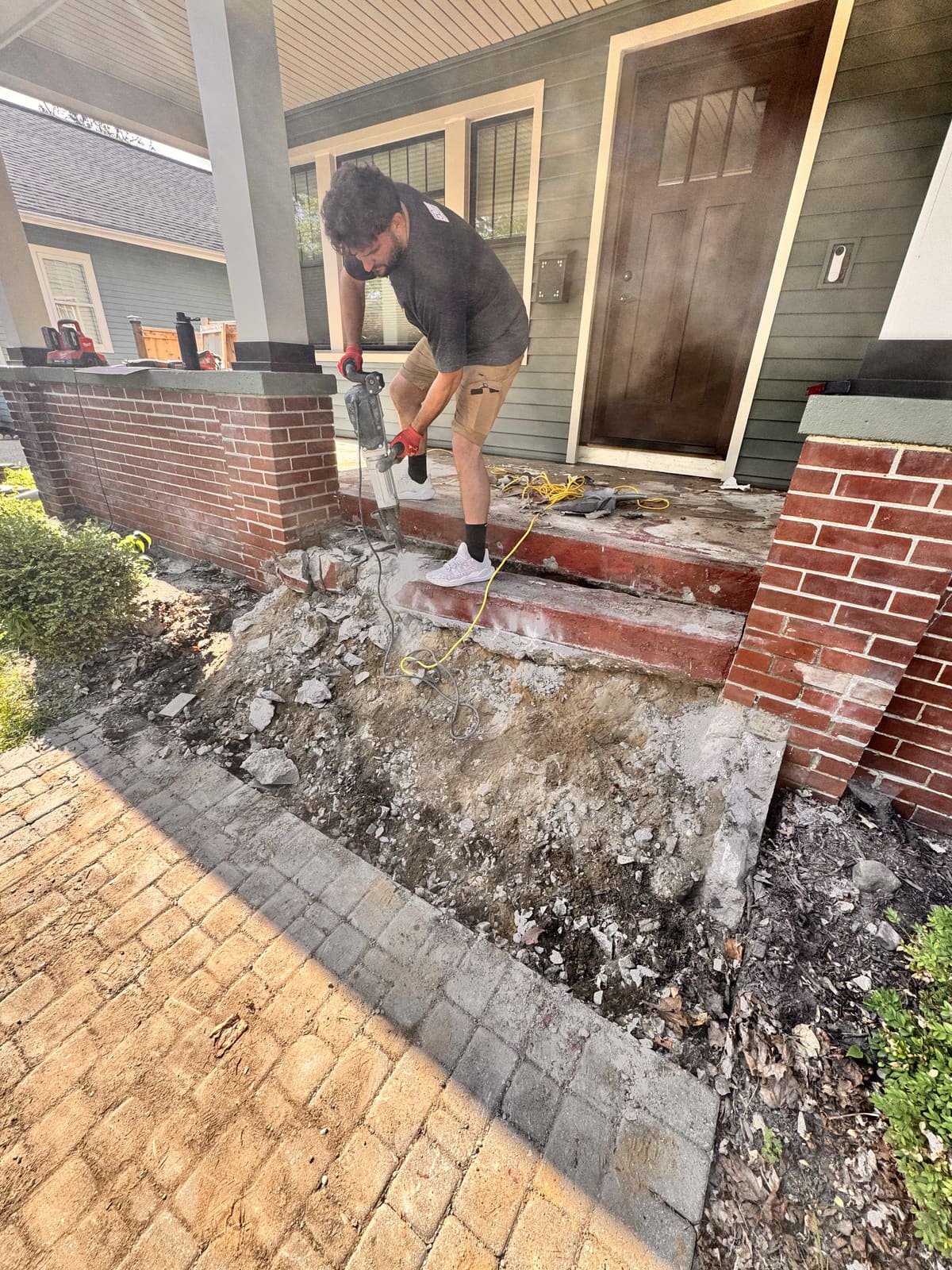 Crew breaking out brick steps at the front of a house