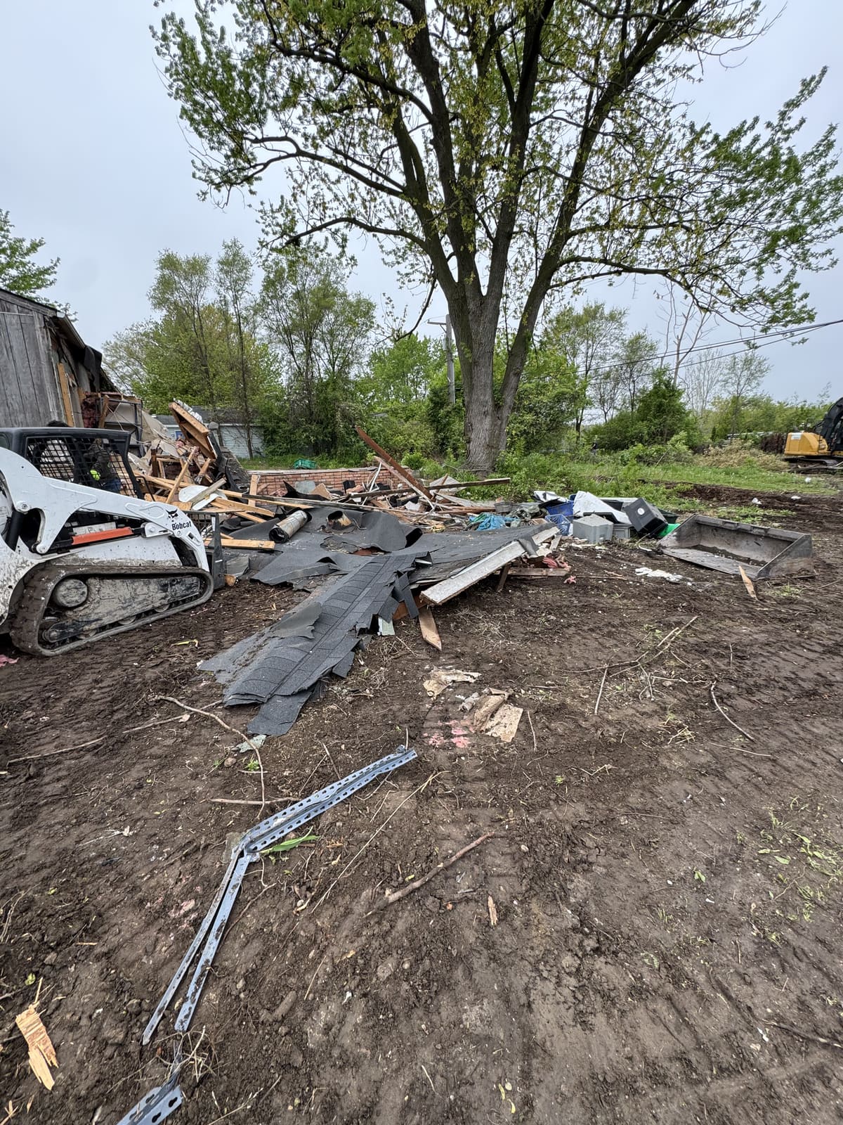 Debris pile and a skid steer during an outbuilding demolition
