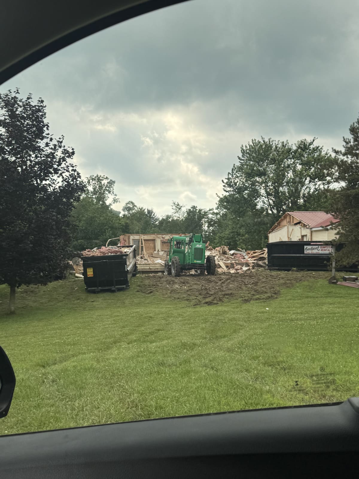 Backyard demolition with equipment and dumpsters on the grass