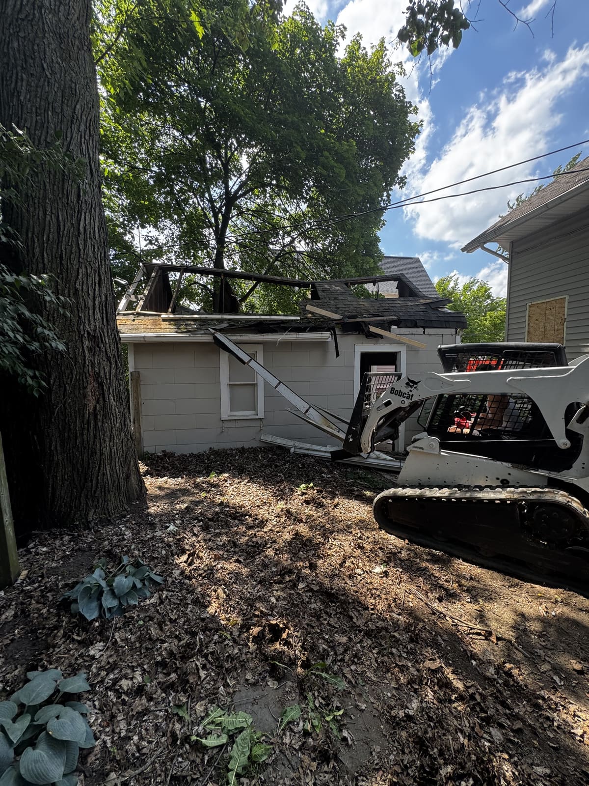 Skid steer pushing into the side of a garage